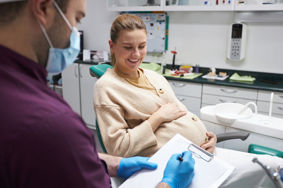 Pregnant patient smiling during dental consultation with dentist in Queen Creek office.