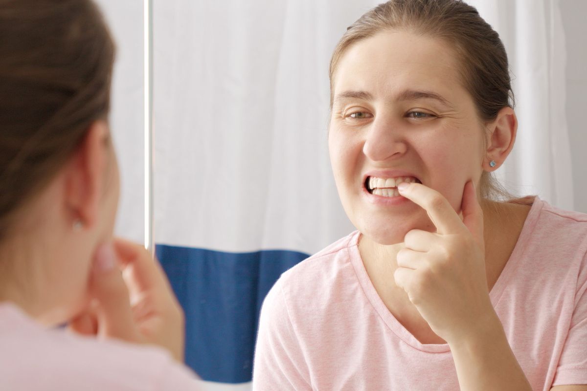 Woman examining her teeth in mirror, concerned about discoloration after whitening treatment.