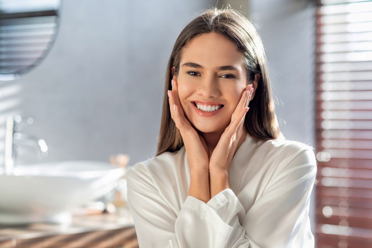 Woman with a bright smile touching her face in a modern dental office setting.